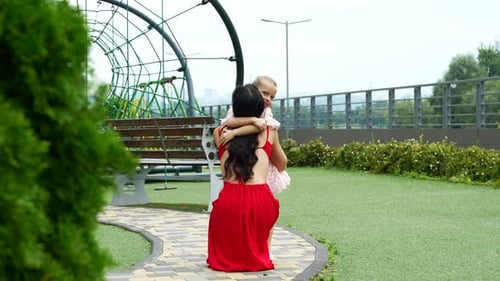 Tender Moment Between Mother and Daughter at Playground on a Sunny Day in Early Summer