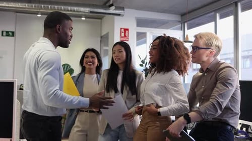 Multiracial coworkers celebrating success in modern office