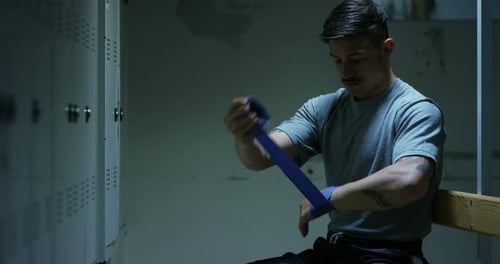 Un joven boxeador profesional en los vestuarios, con las manos cubiertas de vendajes de plástico azules,