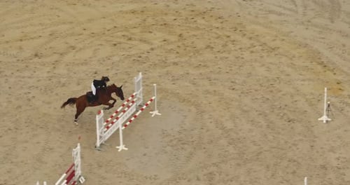Equestrian Rider Jumps Over Obstacles in Aerial Shot
