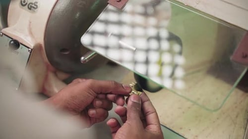 Close up of professional craftsman polishing gold jewellery on workbench, slow motion