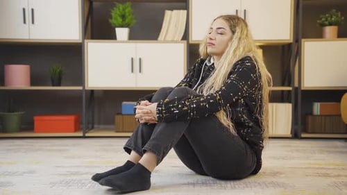 Woman Sits on Floor with Sad Expression