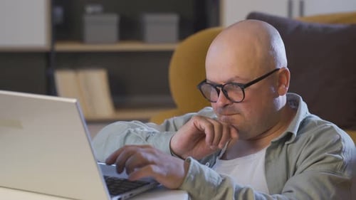 Bald Man Typing on Laptop at Home
