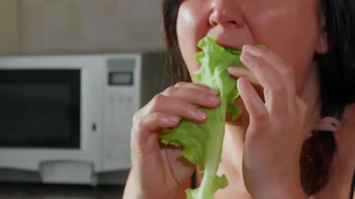 Woman Examining Fresh Green Lettuce Leaf in Modern Kitchen Close Up