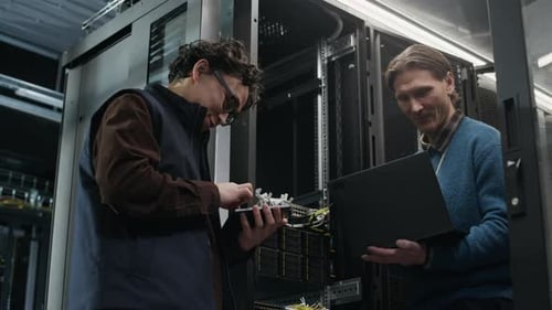 Data Center Engineers Working with Laptop near Server Rack