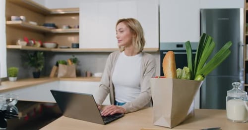 Woman Uses Laptop in Bright Modern Kitchen