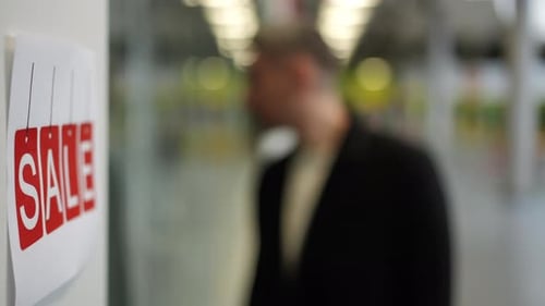 Man Standing Near Sale Sign in a Store Inside a Modern Shopping Mall