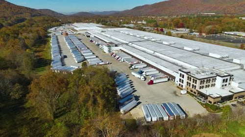 Top View of Giant Logistics Center with Many Commercial Trailer Trucks Unloading and Uploading