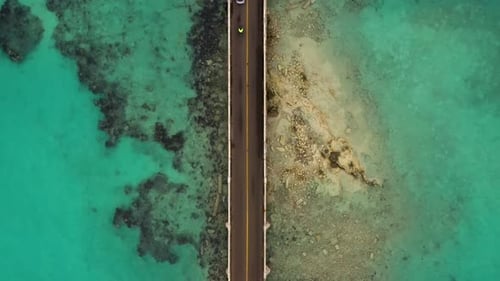 Birds eye view of car bridge over turquoise water on tropical island. DOWN TO UP.