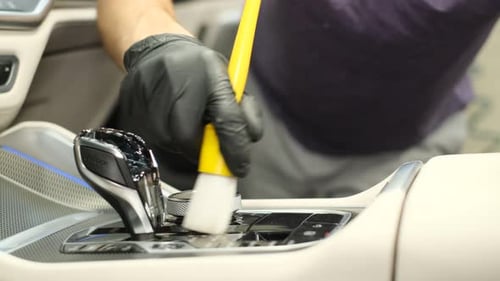 Auto Detailer Cleaning Interior of Car with Brush