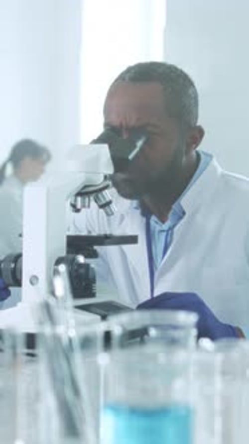 Man Using Microscope in a Brightly Lit Lab