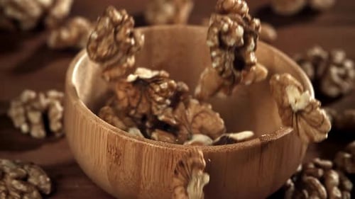 Walnuts Falling Into a Bowl on Wooden Table