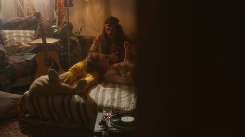 Two Loved-Up Hippies Relaxing and Chatting in Retro Bedroom