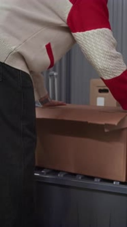 Vertical d'un jeune homme entrant dans l'unité de stockage et triant les articles dans la boîte
