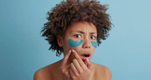 Une femme afro-américaine comprime les boutons et applique des patchs de beauté pour le rajeunissement de la peau