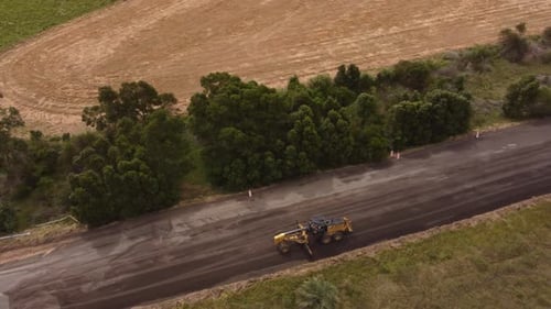 Aerial birds eye shot of Road roller machine built new asphalt road in South America during sunny da