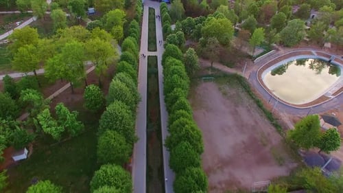 Green town park zone with artificial pond. Walking roads leading to the big shopping mall.