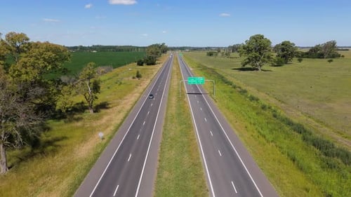 Aerial shot of a tranquil highway through lush countryside on a sunny day