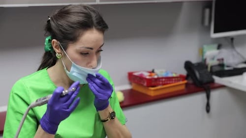 A Healthcare Professional Employed in a Dental Clinic Wearing a Mask and Gloves for Safety