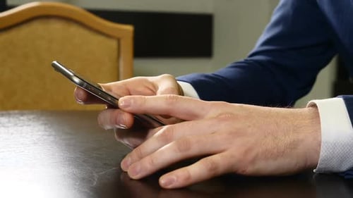 Hands of Man in Suit Holding Black Smartphone