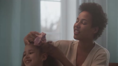 Woman Styles Laughing Girl's Hair Indoors