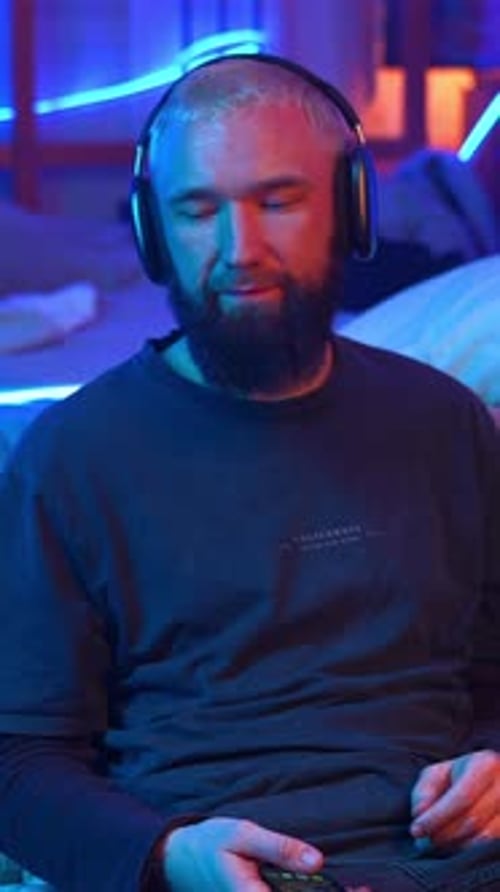 Young Bearded Blond Man Sitting on the Floor By His Bed Media Man Shaking Head While Listening Music