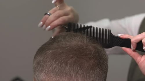 Hairdresser Cutting Man's Hair with Scissors and Comb