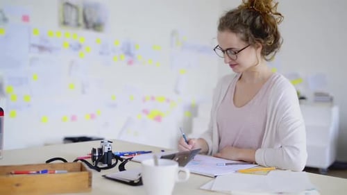 Woman Drawing Artistically at Desk in Bright Room