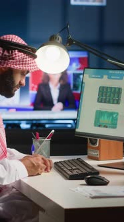 Man Typing at Computer in a Dimly Lit Office