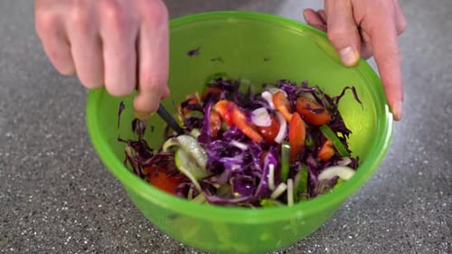 Closeup of human hands cooking in the kitchen. Chef mixing salad of vegetables in a bowl. Healthy ve