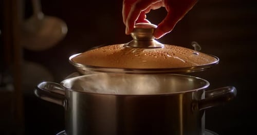 Slow motion scene of a boiling pot steams up as a restaurant's chef cooking in the morning.