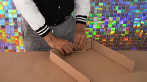 Personne assemblant une boîte en carton pour l'emballage avec un fond holographique coloré