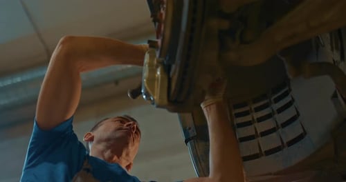 Mechanic Technician Works on Repairing the Chassis of a Car in a Garage a Vehicle Inspection Station