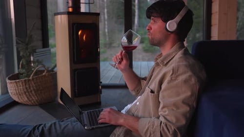 Man Using Laptop and Drinking Wine Indoors
