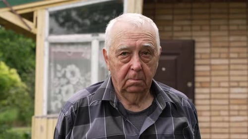 Senior Man Standing Outside Brick Building, Close Up