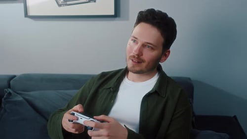 Man Plays Video Game on Couch at Home
