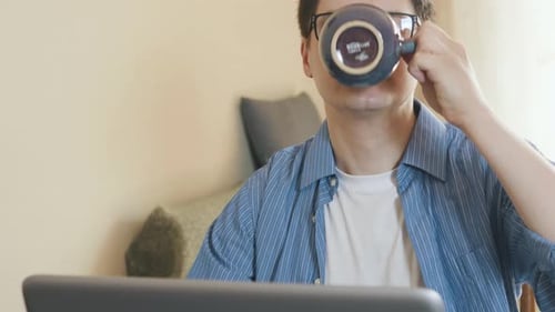 Young Adult Works on Laptop and Drinks Coffee