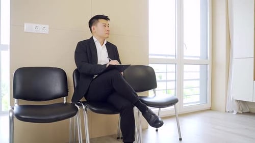 young asian male a business formal suit in waiting room for interview or meeting. Thoughtful busines