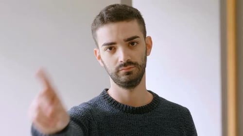 young bearded man looking at camera and saying no with finger