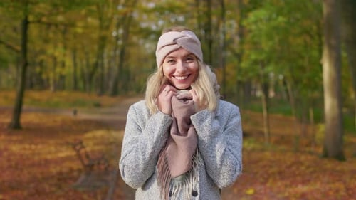 Smiling Young Lady Walking in Park in Autumn