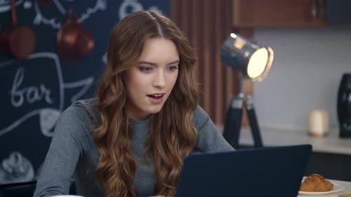 Woman Using Laptop in Kitchen With Chalkboard Wall