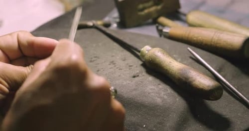 Nahaufnahme einer Hand eines Goldschmieds, der ein kostbares Juwel mit wertvollen Diamanten baut. Um das zu machen