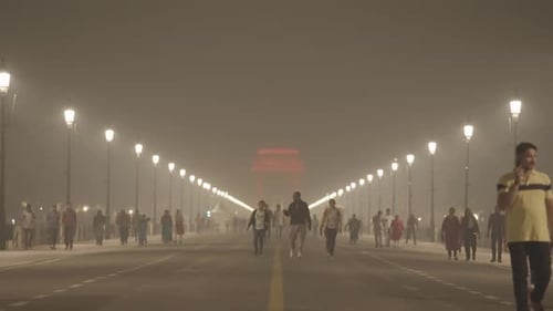 People Walking Down Road with Streetlights at Night