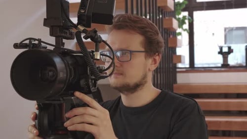 Man Adjusting a Large Professional Video Camera