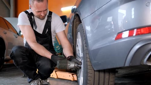The Auto Repairer Installs or Dismantles Wheels in the Workshop Car Repair and Maintenance