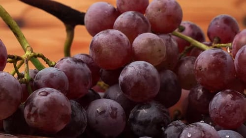 Red grapes rotate on a wooden background.