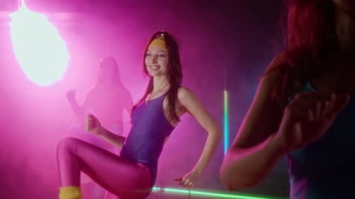 Smiling Women Exercising in Neon Lit Studio