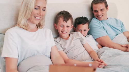 Smiling Family Watching Tablet Together in Bed