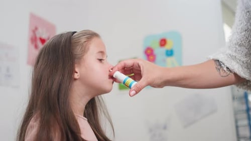 Child Receiving Nasal Spray from Adult Indoors