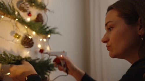 Woman Decorating DIY Christmas Tree with Pine Sprigs